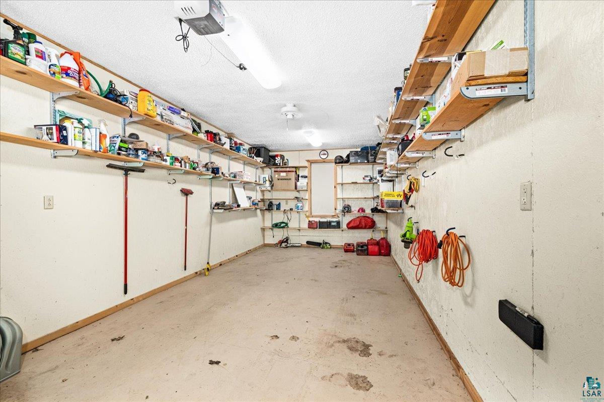 3799 South Lake Road Moose Lake, MN 55767 - Photo 34 of 35 Garage interior featuring concrete flooring, extensive wall-mounted shelving, and overhead lighting fixtures