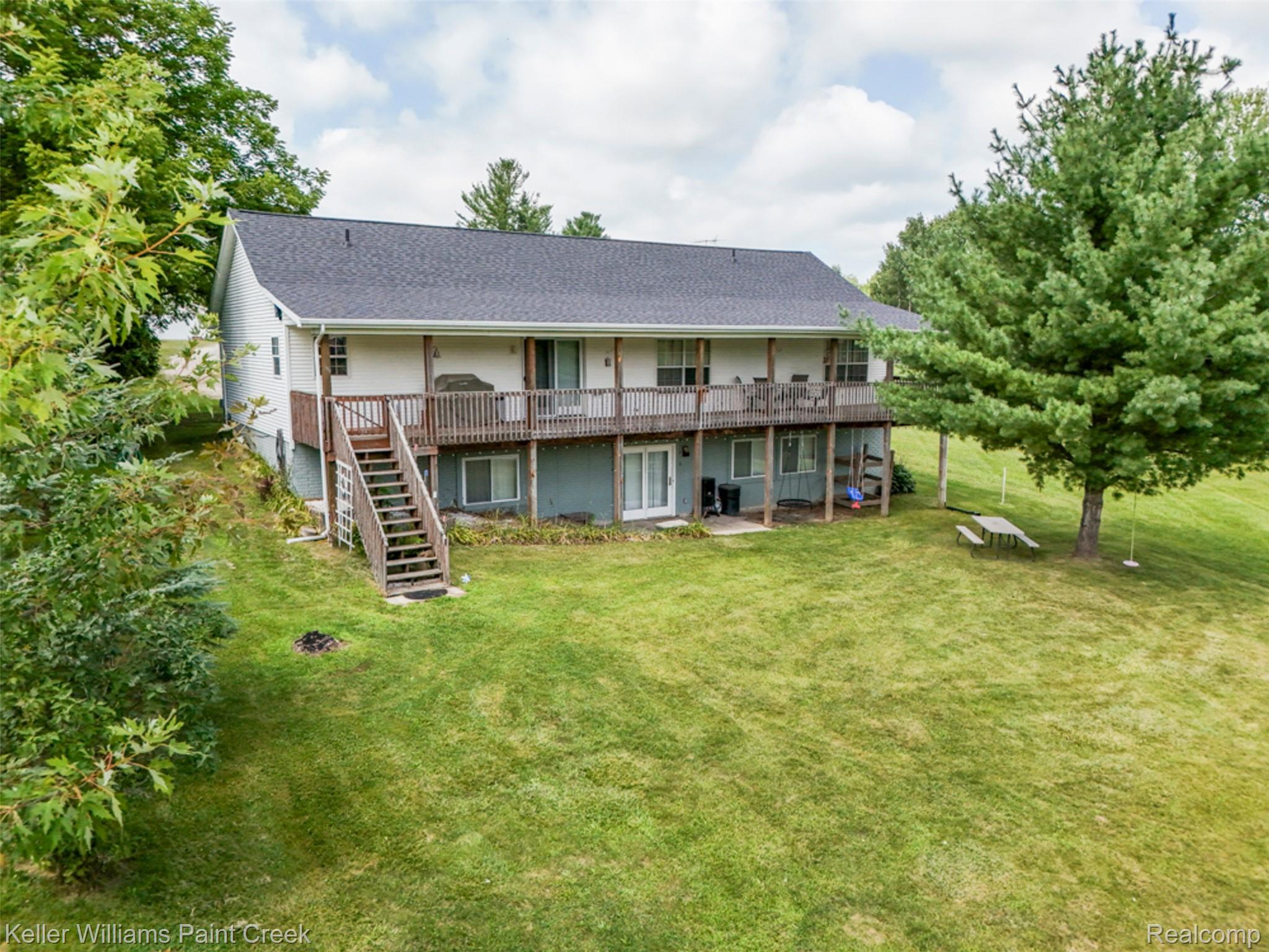 533 White Road Gladwin, MI 48624 - Photo 60 of 69 Rear exterior with a full-width upper-level deck, lower patio area, and a walk-out basement