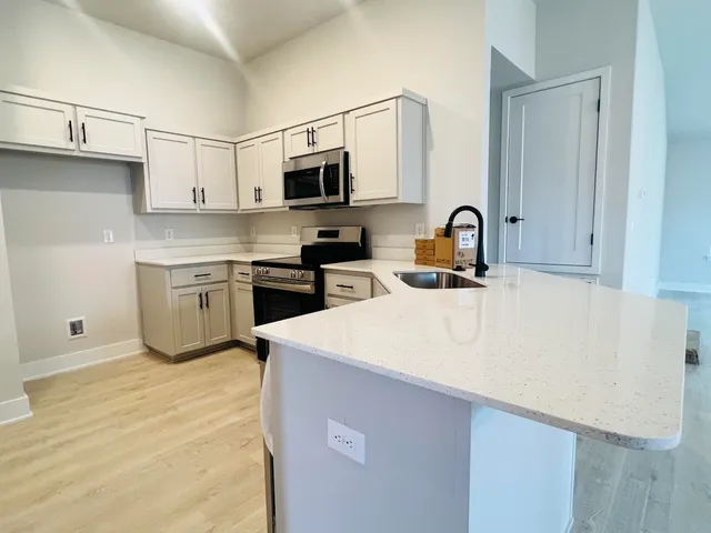 a kitchen with stainless steel appliances a sink a stove top oven a counter space and cabinets