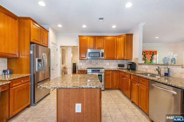 a large kitchen with stainless steel appliances granite countertop a sink counter space cabinets and a large window