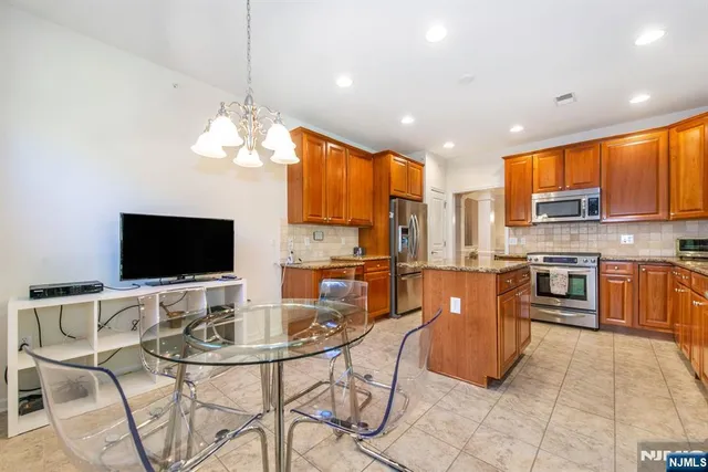 a kitchen with stainless steel appliances granite countertop a stove top oven a sink dishwasher a dining table and chairs with wooden floor