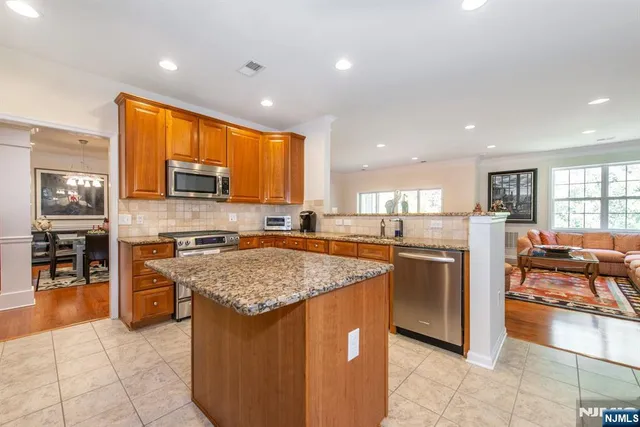 a kitchen with stainless steel appliances granite countertop a stove top oven a sink a counter top space cabinets and living room view