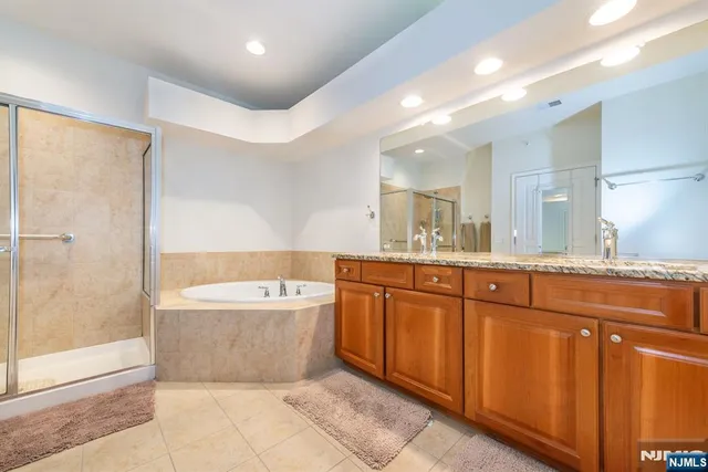 a spacious bathroom with a tub sink shower and mirror