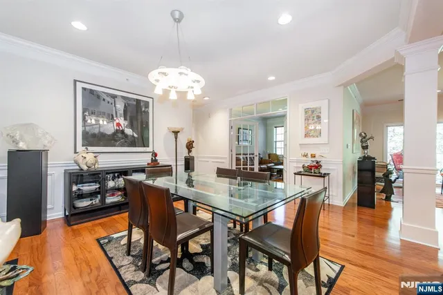 a dining room with wooden floor a chandelier a wooden table and chairs