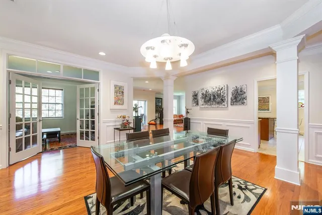 a dining room with wooden floor and large windows