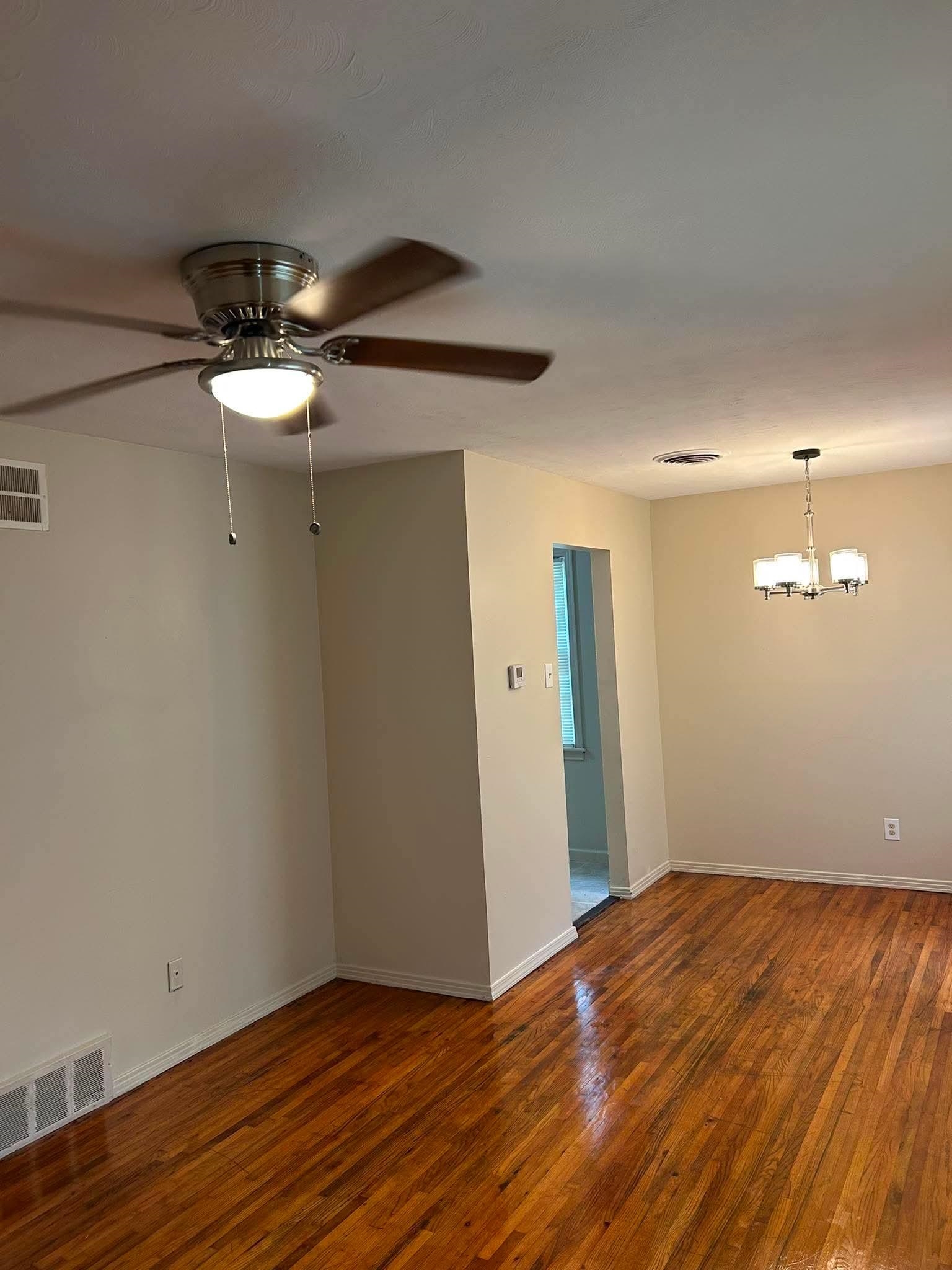 1510 Gausco Road Memphis, TN 38106 - Photo 2 of 10 Hardwood flooring throughout featuring a ceiling fan with integrated lighting, a contemporary chandelier, baseboard molding, and neutral wall tones