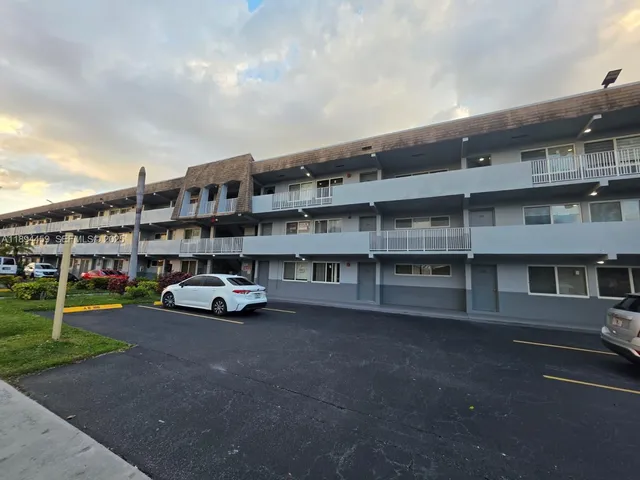 a view of building with cars parked in front of it