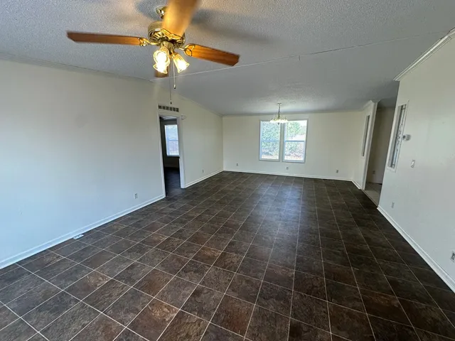 a view of an empty room and window with a chandelier fan