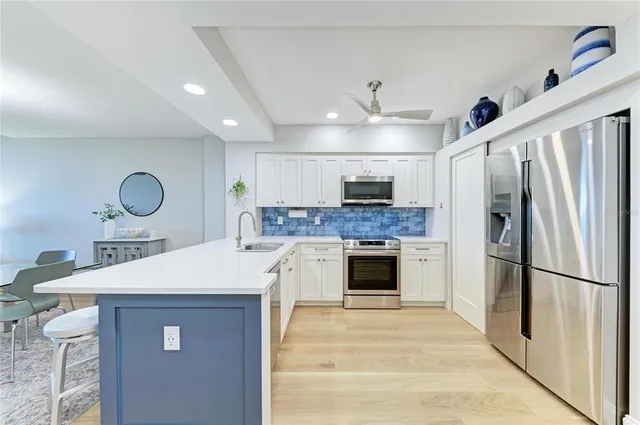 a kitchen with a sink stainless steel appliances and ceiling fan