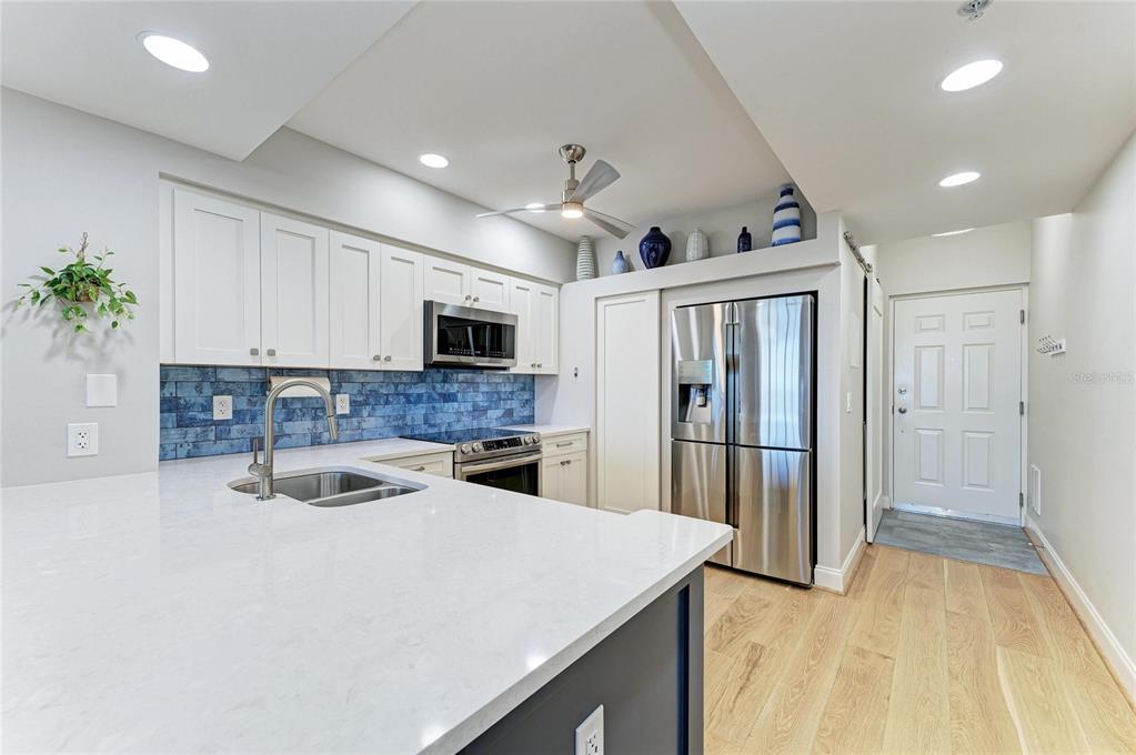3191 Matecumbe Key Road, Unit 307 Punta Gorda, FL 33955 - Photo 12 of 40 a kitchen with granite countertop a refrigerator a sink dishwasher and white cabinets with wooden floor