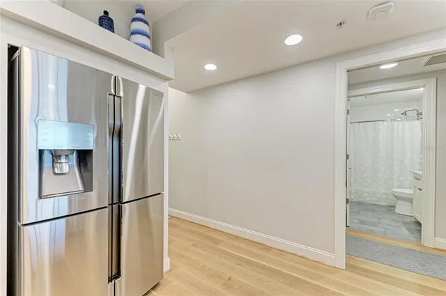a view of a refrigerator in kitchen and an empty room