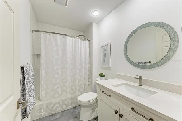 a bathroom with a granite countertop toilet a sink and a mirror