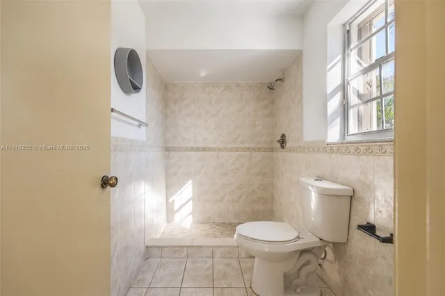 a white toilet sitting next to a shower