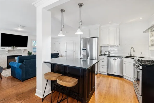 a kitchen with stainless steel appliances a stove a sink a microwave a refrigerator and chairs