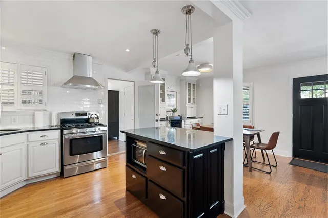 a kitchen with stainless steel appliances a stove a sink a dining table and chairs