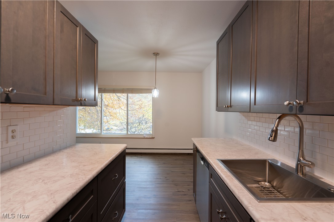 Kitchen with sink, tasteful backsplash, dark hardwood / wood-style flooring, pendant lighting, and dark brown cabinets