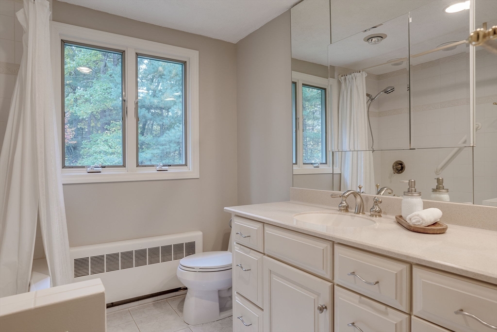 16 Fox Run Road Bedford, MA 01730 - Photo 27 of 37 a bathroom with a granite countertop toilet a sink a mirror and a window