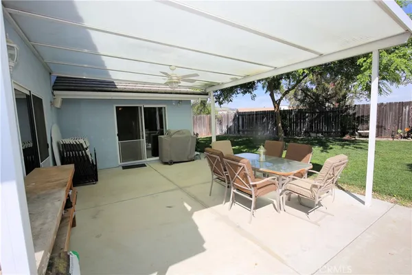 a view of a patio with a table and chairs under an umbrella next to a yard