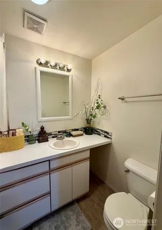 a bathroom with a granite countertop toilet sink and mirror