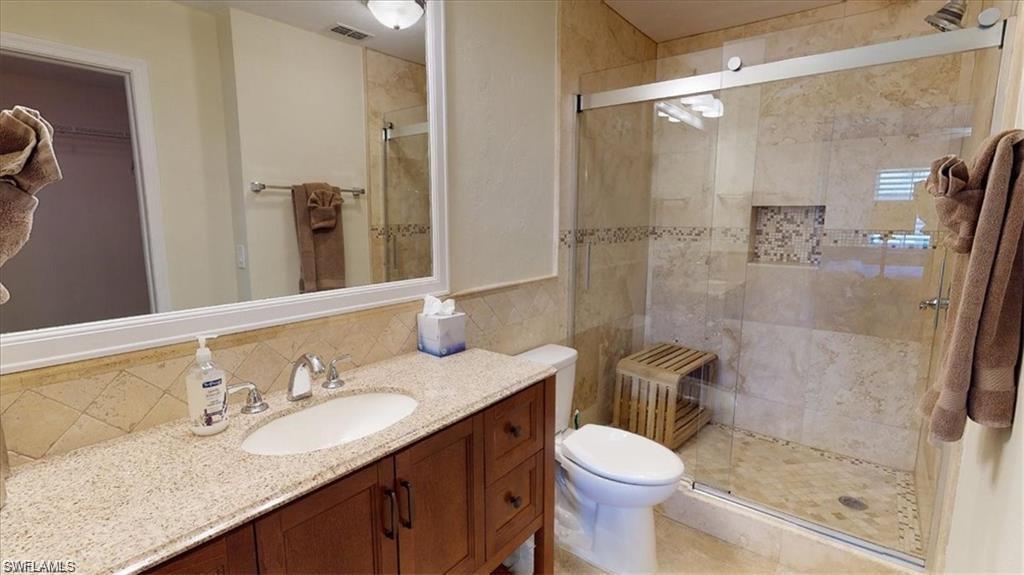 4180 Looking Glass Lane, Unit 4104 Naples, FL 34112 - Photo 14 of 30 a bathroom with a granite countertop toilet sink and shower