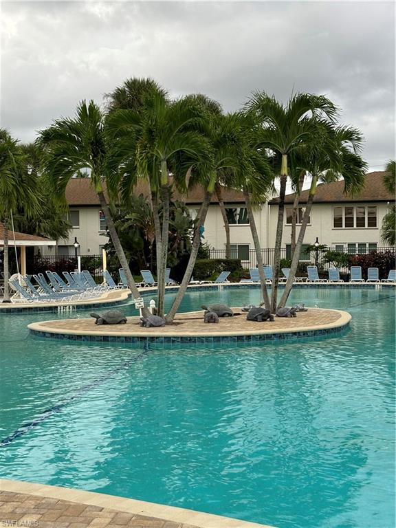 4180 Looking Glass Lane, Unit 4104 Naples, FL 34112 - Photo 24 of 30 a view of a swimming pool with a lawn chairs under palm trees
