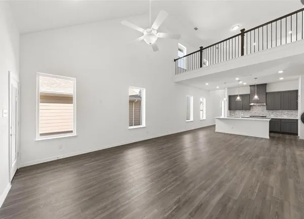 a view of an empty room with kitchen and window
