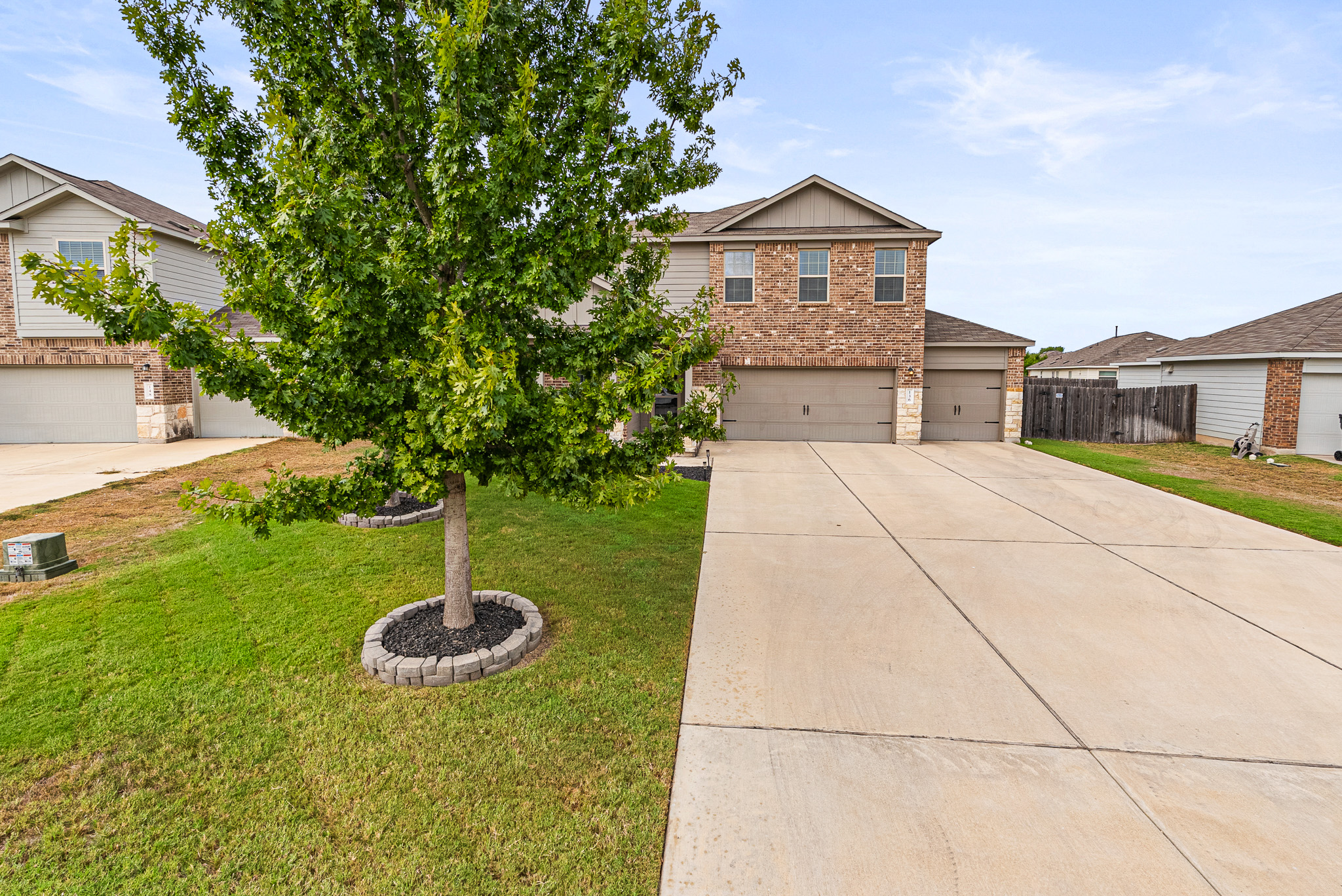 136 Copper Lane Kyle, TX 78640 - Photo 3 of 33 View of front facade featuring concrete driveway, brick siding, roof with shingles, an attached garage, and stone siding