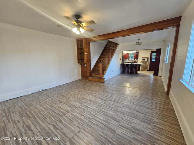 a view of an empty room with stairs and a ceiling fan