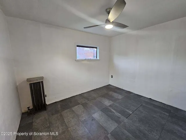 an empty room with a ceiling fan and window