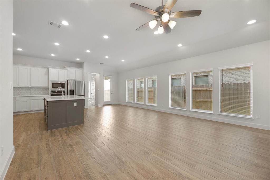 123 Plumbago Loop Bastrop, TX 78602 - Photo 39 of 40 a view of an empty room with wooden floor and a kitchen