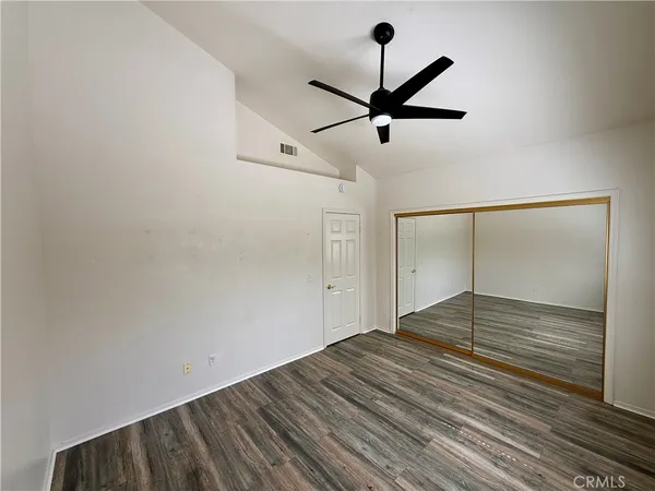 a view of empty room with wooden floor and ceiling fan