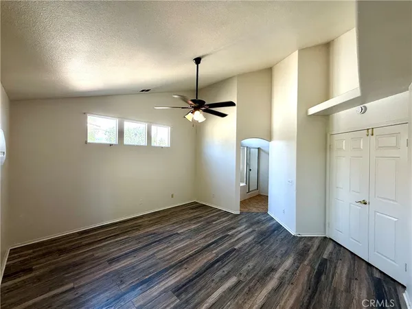 a view of empty room with wooden floor and ceiling fan