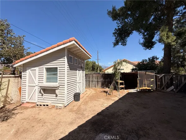 a backyard of a house with table and chairs under an umbrella