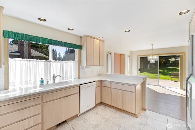 a large white kitchen with a sink and a large window