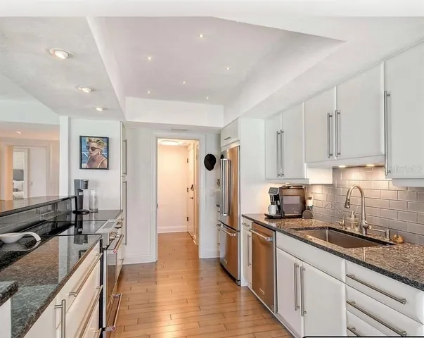 a kitchen with granite countertop a sink stove and cabinets
