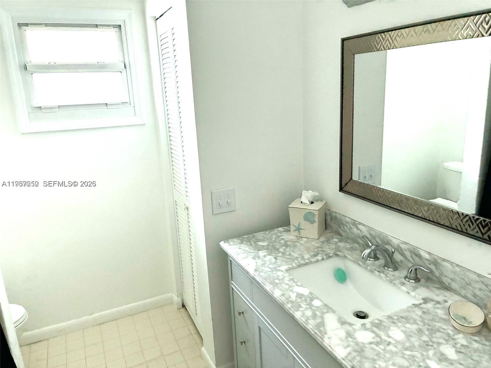 4541 Southwest 28th Terrace Dania Beach, FL 33312 - Photo 8 of 9 a bathroom with a granite countertop sink and a mirror