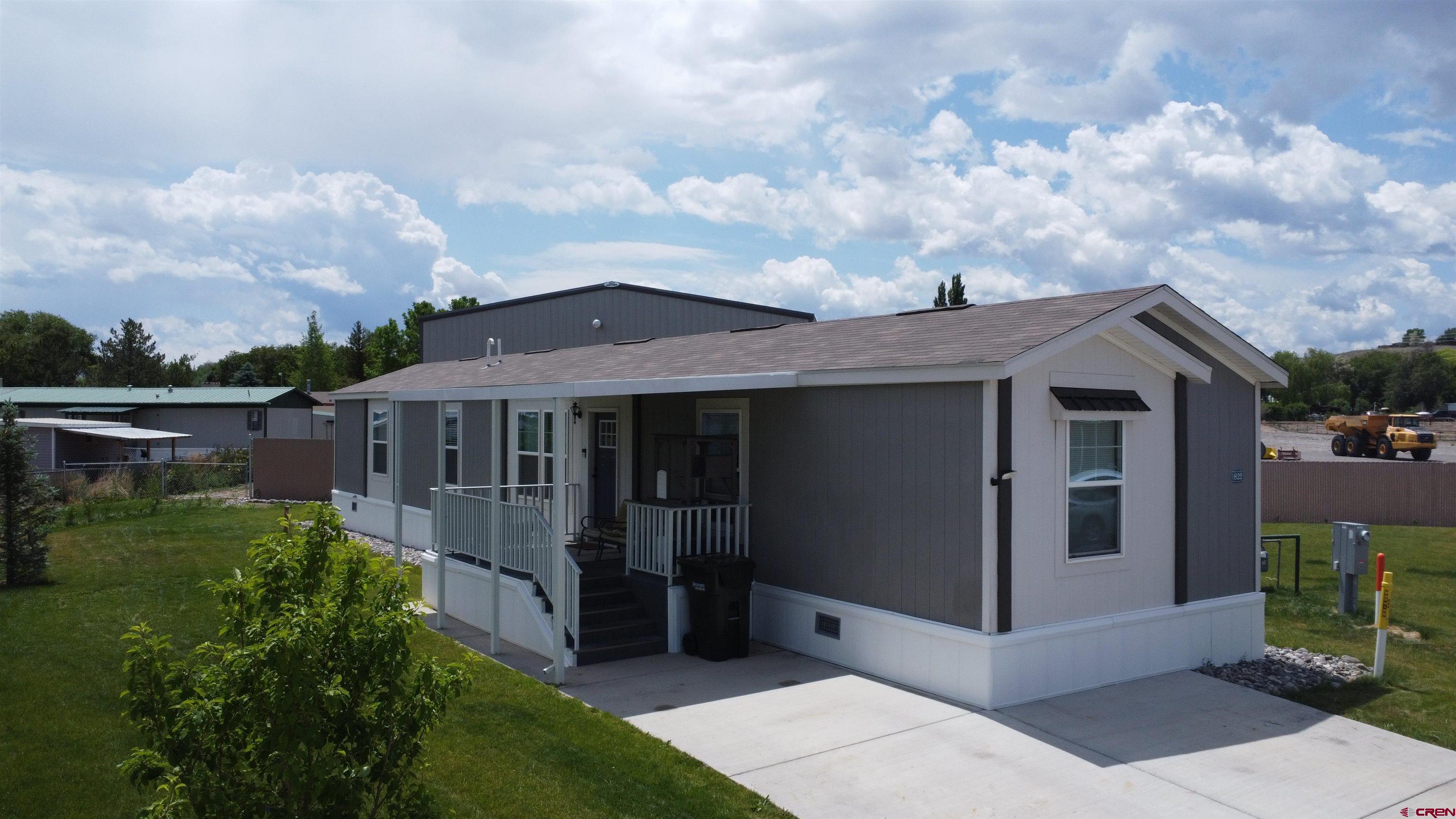 62650 Lasalle Road, Unit 822 Montrose, CO 81403 - Photo 2 of 17 a view of a white house with a big yard and potted plants