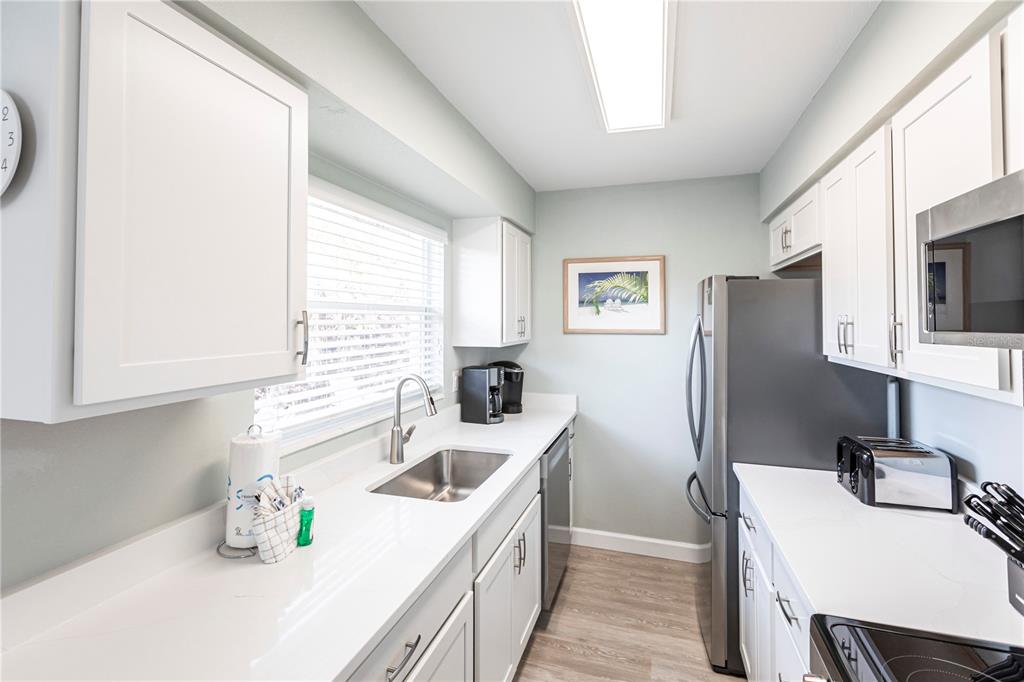 6020 Midnight Pass Road, Unit 11 Sarasota, FL 34242 - Photo 11 of 29 a kitchen with a sink a refrigerator and cabinets