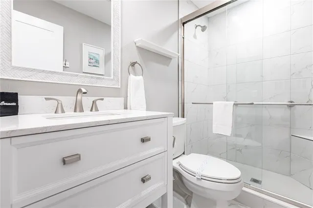 a bathroom with a sink a toilet a mirror and shower