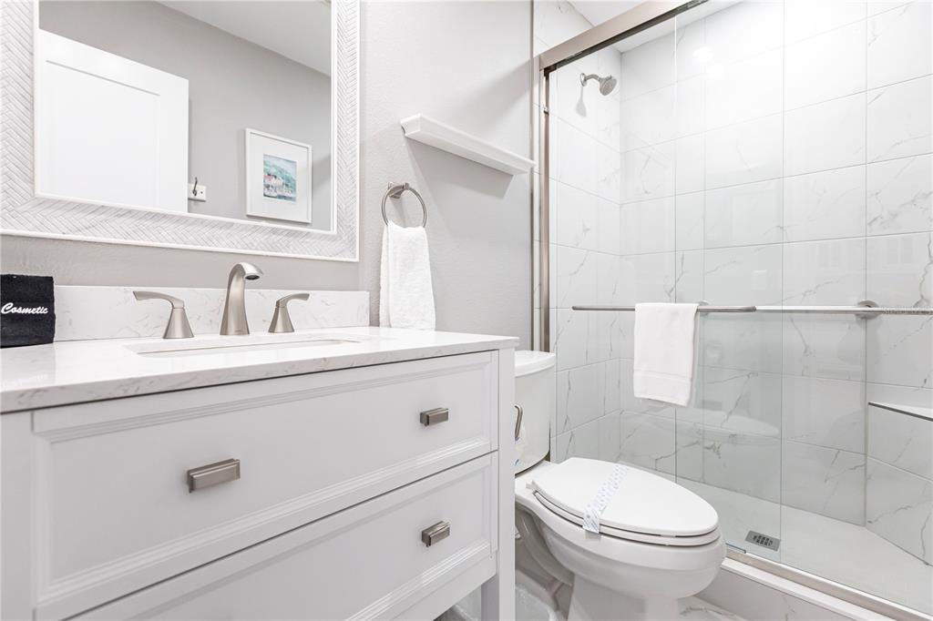 6020 Midnight Pass Road, Unit 11 Sarasota, FL 34242 - Photo 19 of 29 a bathroom with a sink a toilet a mirror and shower