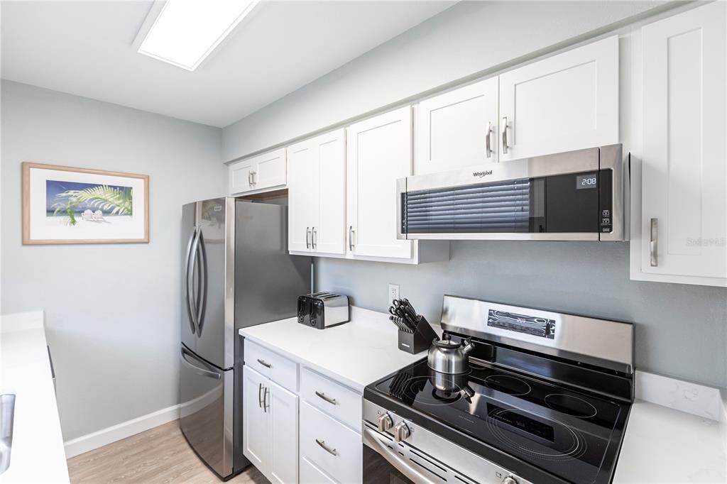 6020 Midnight Pass Road, Unit 11 Sarasota, FL 34242 - Photo 10 of 29 a kitchen with stainless steel appliances a refrigerator a stove a microwave and cabinets