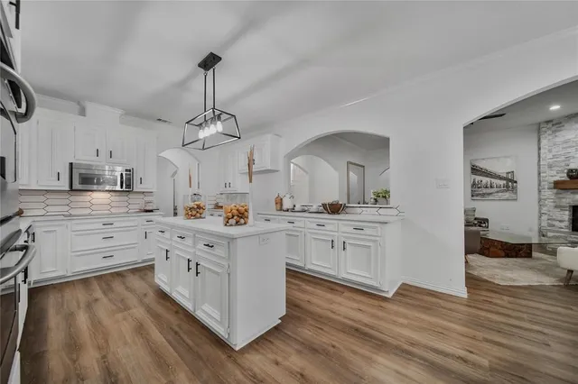 a kitchen with white cabinets and wooden floor
