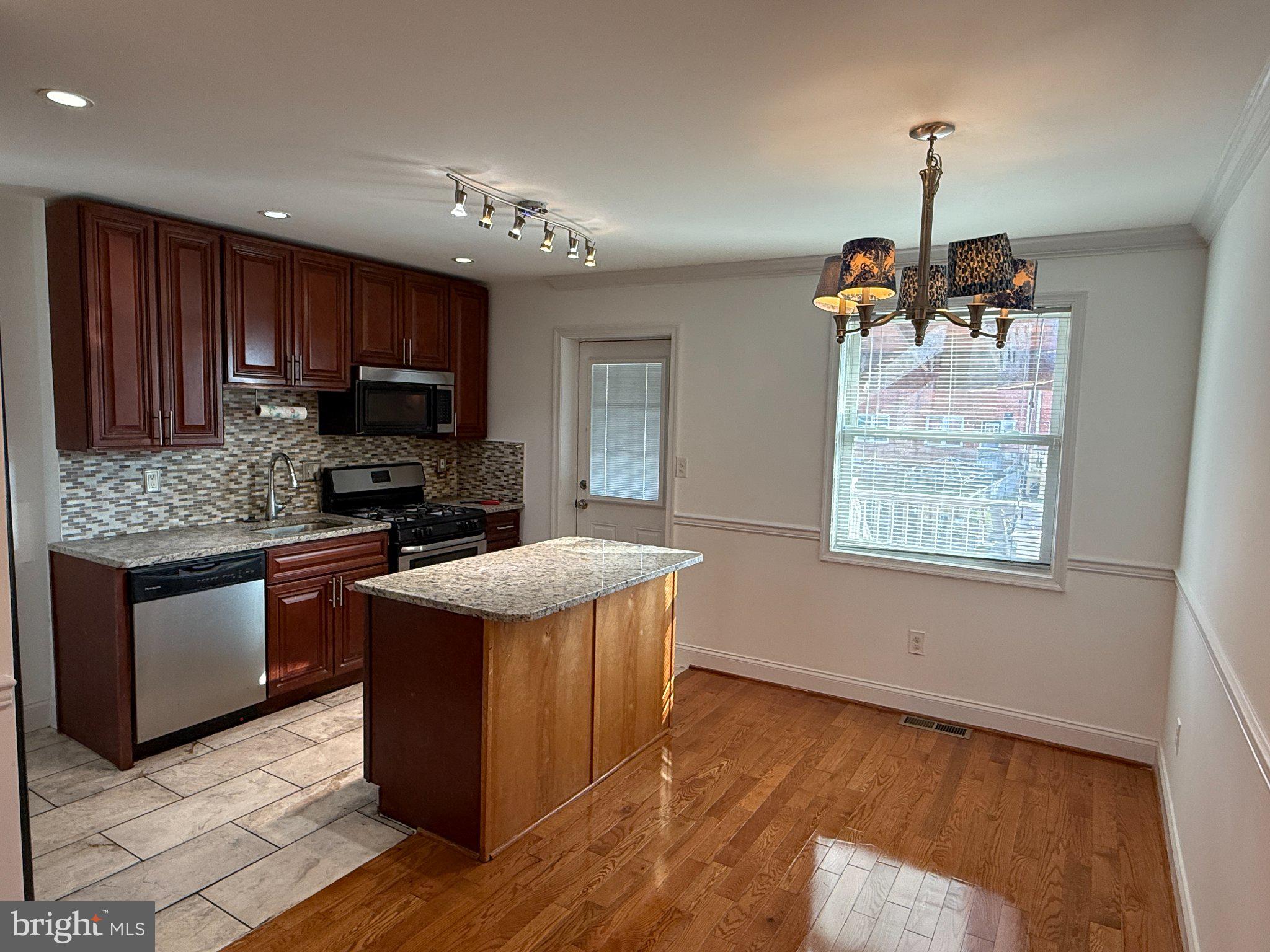 1907 Penhall Road Dundalk, MD 21222 - Photo 34 of 64 a kitchen with kitchen island granite countertop wooden floors and stainless steel appliances