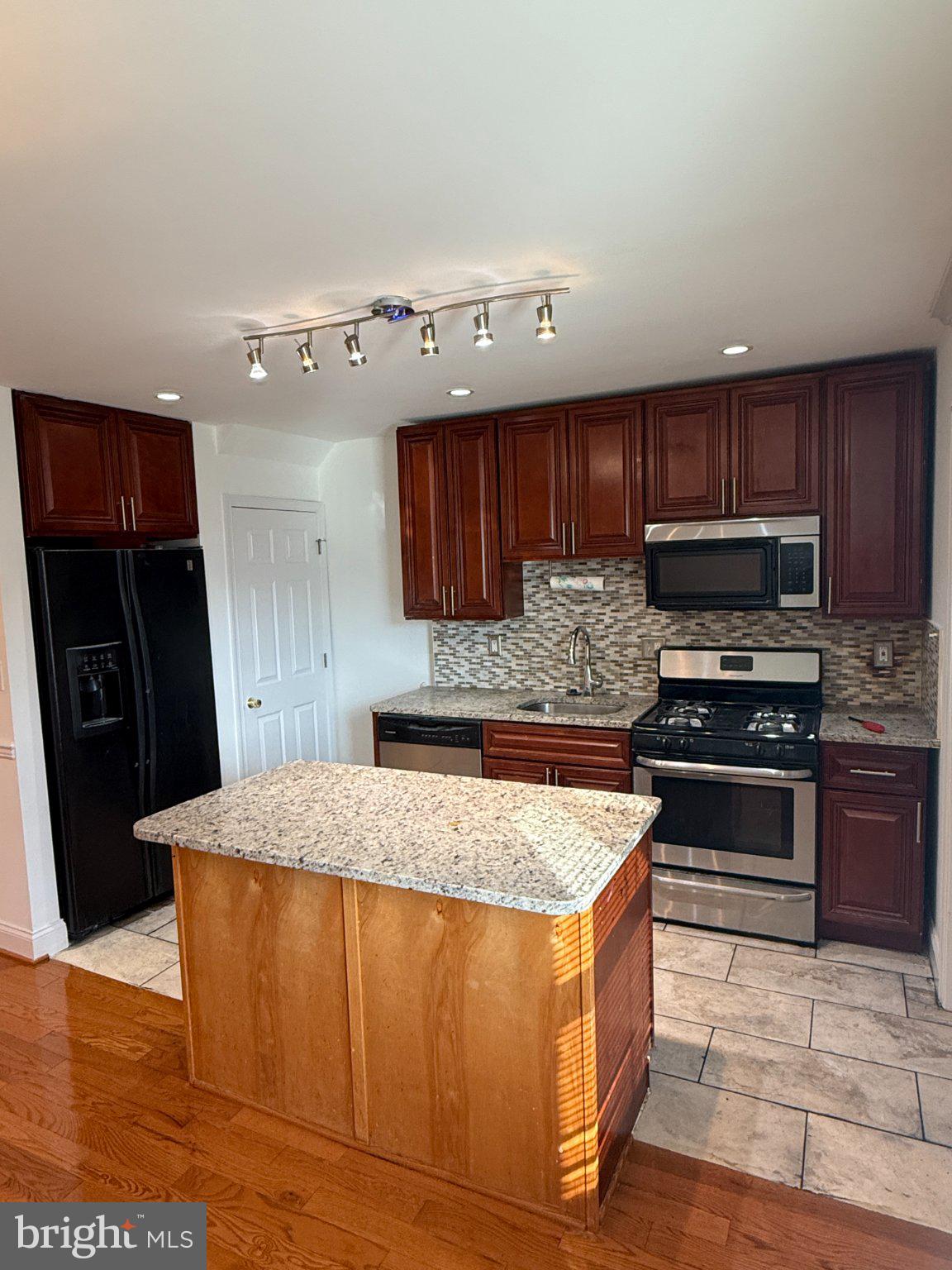 1907 Penhall Road Dundalk, MD 21222 - Photo 40 of 64 a kitchen with stainless steel appliances granite countertop wooden cabinets a refrigerator and a sink