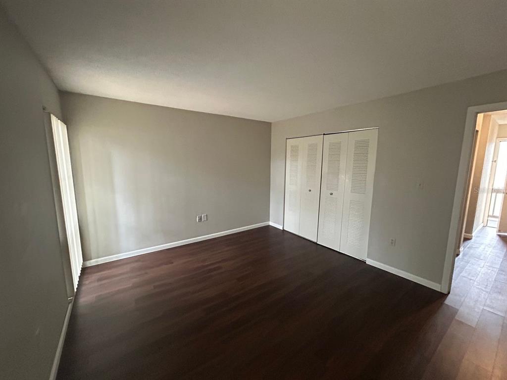 2811 Southwest Archer Road, Unit C18 Gainesville, FL 32608 - Photo 13 of 15 an empty room with wooden floor and windows with curtains