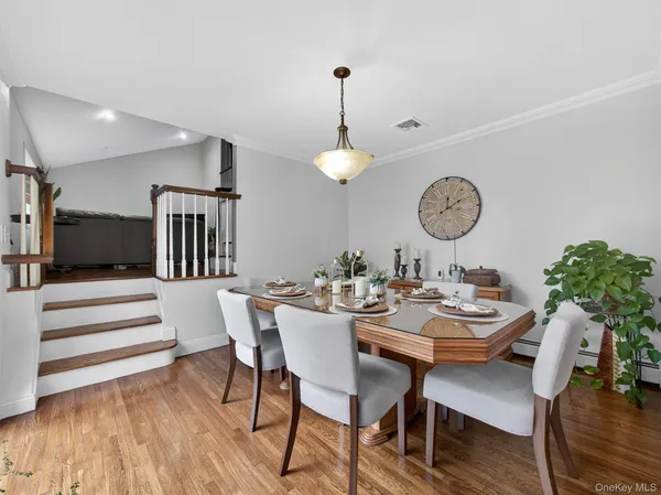 a view of a dining room and livingroom with furniture wooden floor a rug and a chandelier