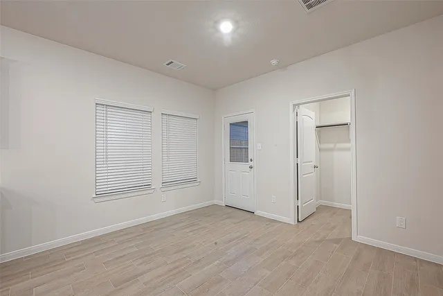 an empty room with wooden floor and windows