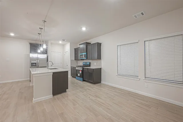 a large kitchen with a large counter top a sink stainless steel appliances and cabinets