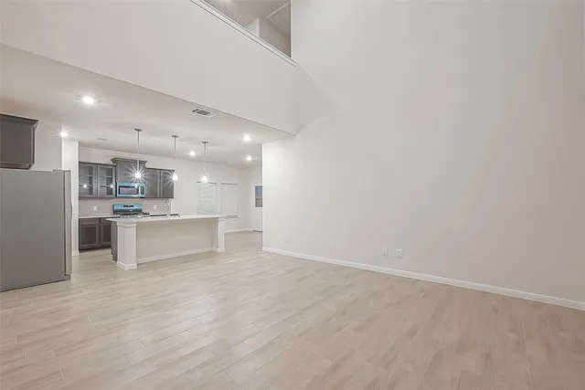 a view of kitchen with kitchen island a sink wooden floor and stainless steel appliances