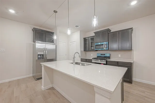 a kitchen with stainless steel appliances a sink a stove a refrigerator cabinets and wooden floor